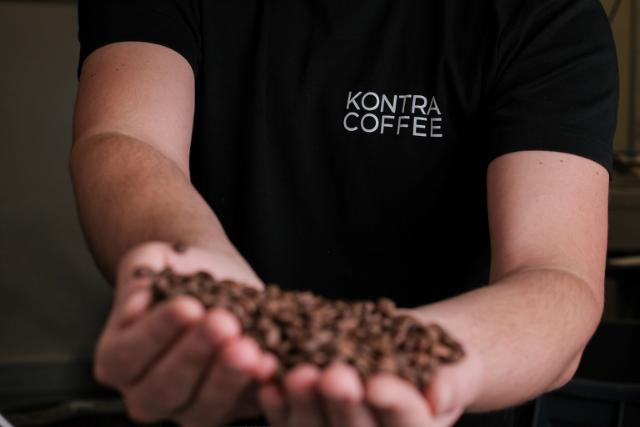 Hænder holder kaffebønner frem mod kameraet 