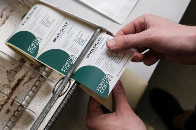 Hånd piller label af rulle med labels til økologisk kaffe
