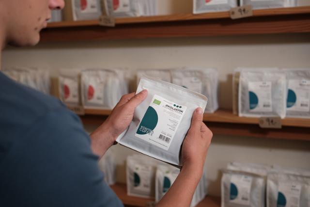 Mellemristede kaffebønner i hvid kaffepose holdes frem af person